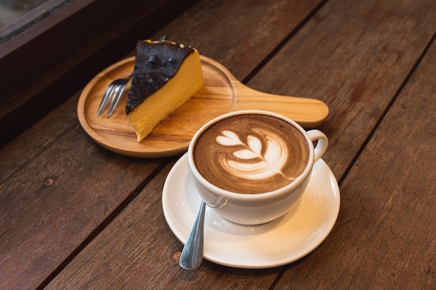 Café au lait chaud avec mousse de lait latte art dans une tasse et gâteau au chocolat fait maison bureau en bois sur un bureau en bois sur la vue de dessus Comme petit-déjeuner Dans un café au concept de travail d'entreprise cafeduring