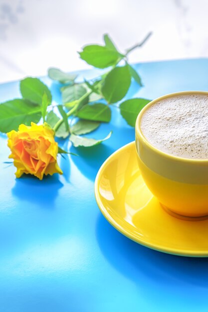 Café au lait de coco et rose jaune sur fond de bois bleu