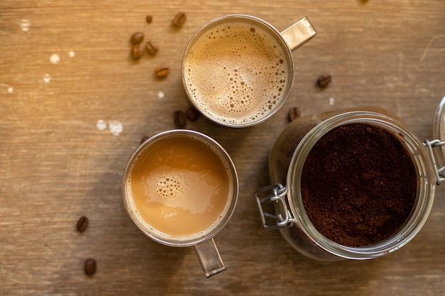 Café au lait dans des tasses en métal sur une vue de dessus de table en bois