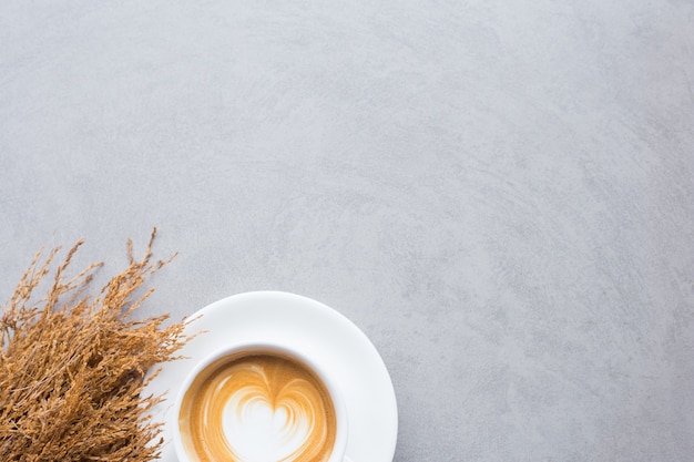 café au lait avec des fleurs séchées sur un sol en béton