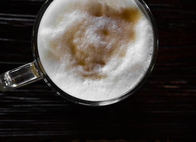 Photo café au lait sur une table en bois noir près de la fenêtre