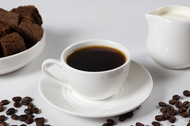 Café au lait une tasse de café et un pot à lait sur fond blanc une place pour le texte un délicieux petit déjeuner