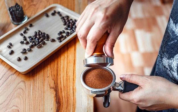 Café barista faisant du café avec des presses manuelles du café moulu à l'aide d'un sabotage sur le comptoir en bois