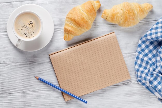 Café et bloc-notes de croissants frais