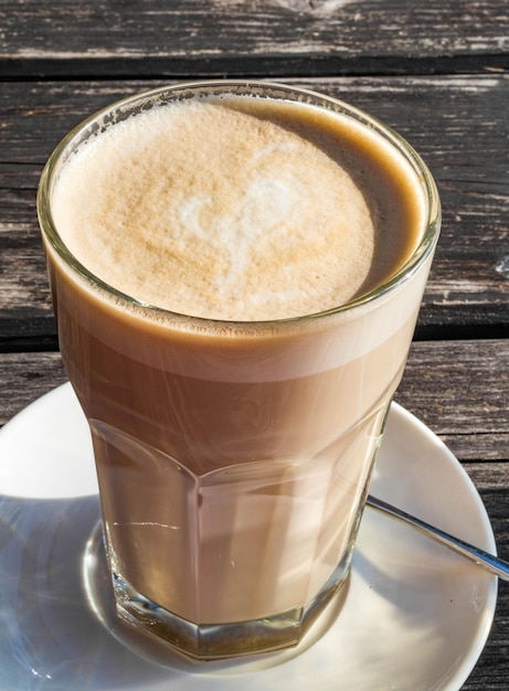 Café café latte macchiato dans un verre haut sur un fond en bois