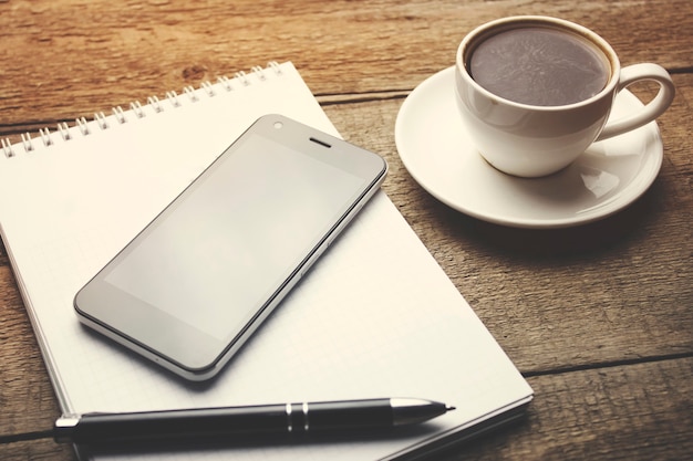 café avec cahier vierge et téléphone sur table en bois