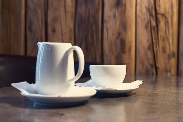 Café cappuccino au lait. Tasse de cappuccino et pot de lait sur fond de bois.