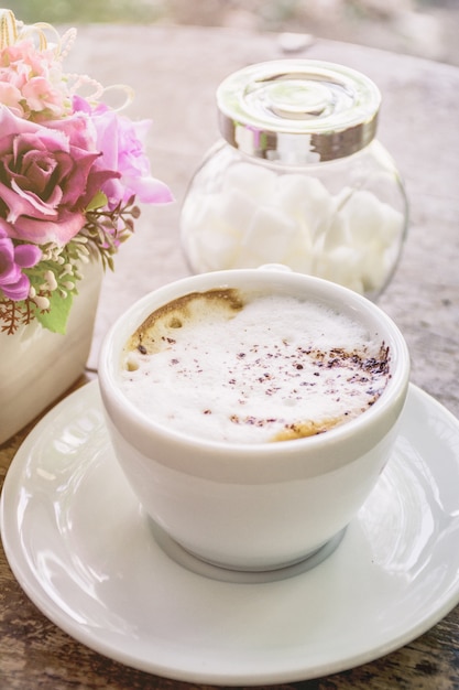 Café cappuccino chaud avec de la mousse sur le dessus de la table en bois