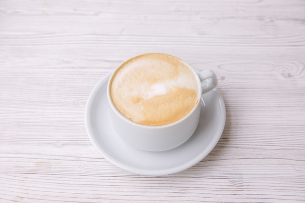 Café cappuccino dans une tasse blanche un menu en bois blanc