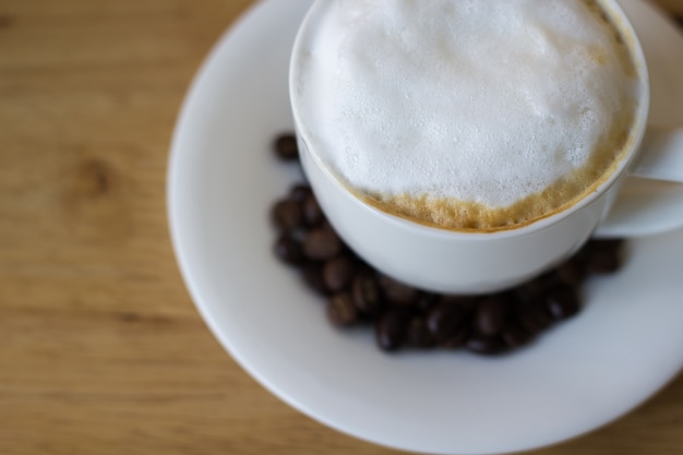 café chaud dans une tasse blanche sur la table avec des grains de café