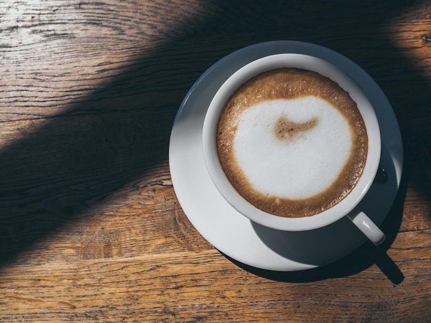 Café chaud dans une tasse en céramique blanche ronde sur fond de table en bois