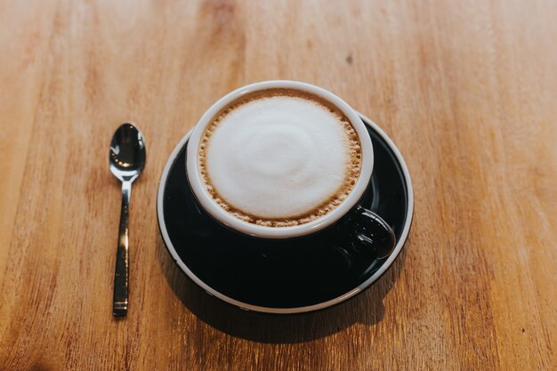 Photo café chaud dans une tasse noire sur une table en bois.