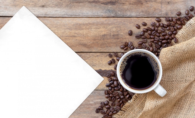 Café chaud et haricots sur fond en bois. vue de dessus