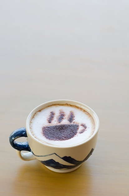 café chaud avec motif de mousse sur la table en bois