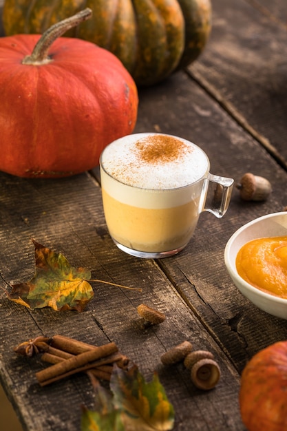 Photo café à la citrouille dans une tasse en verre et crème fouettée à la cannelle. menu cappuccino ou latte d'automne