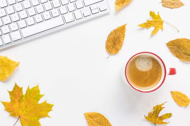 Café de clavier d'ordinateur et feuilles d'automne jaunes