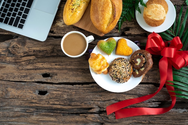 Café croissants, petits pains à la cannelle et petits-déjeuners aux baies Sur une table en bois Avec bloc-notes pour votre tex