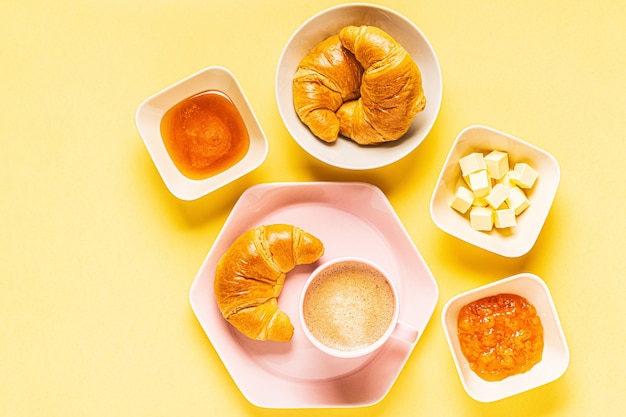 Café et croissants pour le petit déjeuner sur fond jaune