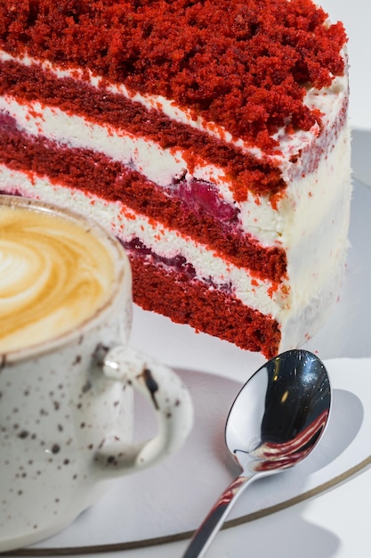 Café, cuillère, une tranche de gâteau sur la plaque sur le fond blanc.