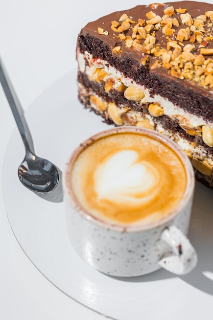 Café, cuillère, une tranche de gâteau sur la plaque sur le fond blanc.