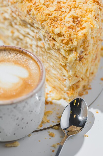 Café, cuillère, une tranche de gâteau sur la plaque sur le fond blanc.