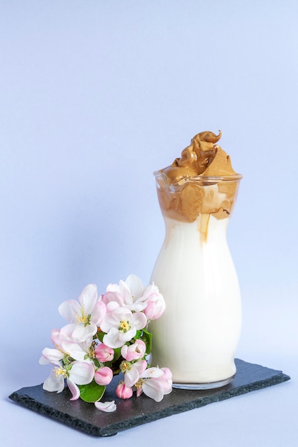 Photo café dalgona froid fouetté à la mode en verre avec des fleurs de pommier