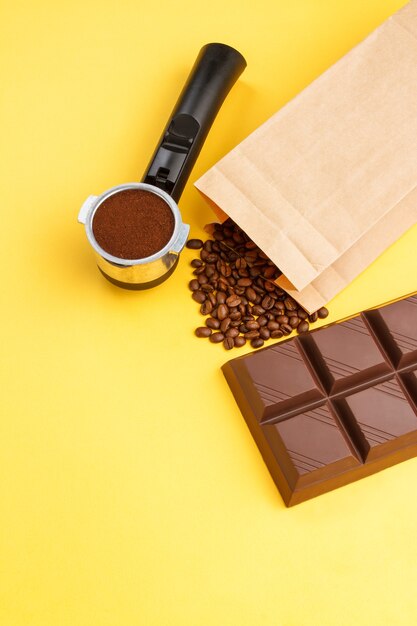 Café dans un support, grains de café, barre de chocolat sur fond jaune