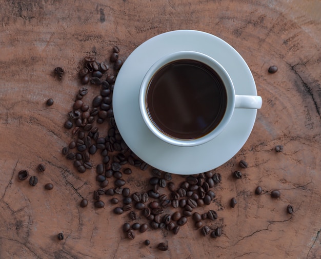 Café dans une tasse blanche et grains de café sur une table en bois