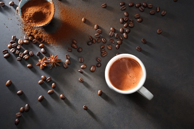 Café dans une tasse blanche et grains de café sur la table.