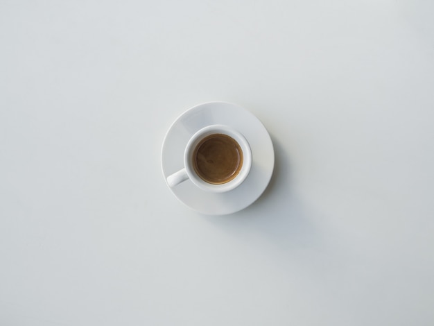 Le café dans une tasse blanche se dresse sur un tableau blanc.