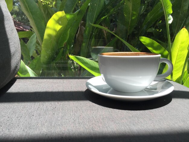 Café dans une tasse blanche sur une table en bois dans un café avec un fond d'éclairage