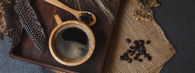 Café dans une tasse en bois et graines avec un sac sur fond de tableau noir au café