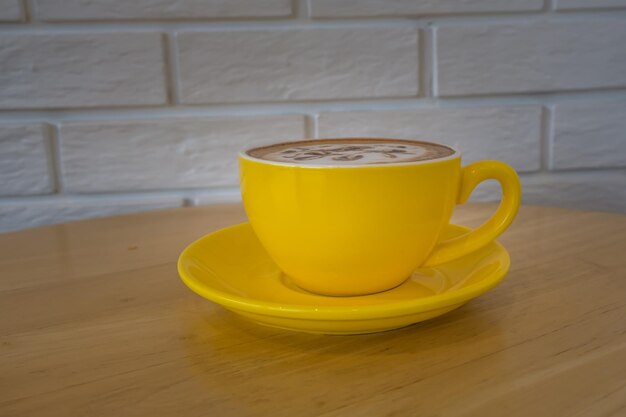 Café dans une tasse jaune sur une table en bois