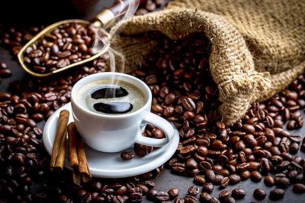 Café dans une tasse et une soucoupe sur fond noir