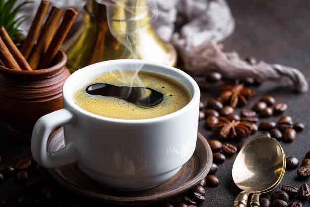 Café dans une tasse et une soucoupe sur fond noir