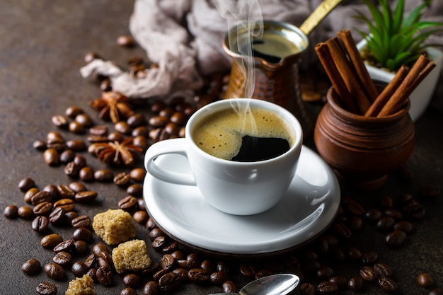 Café dans une tasse et une soucoupe sur fond noir