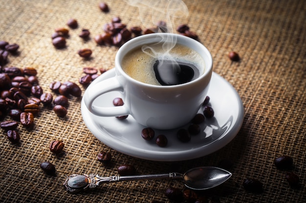 Café dans une tasse et une soucoupe avec des grains de café