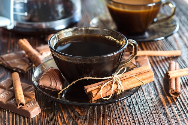 Café dans une tasse en verre et cannelle sur la table