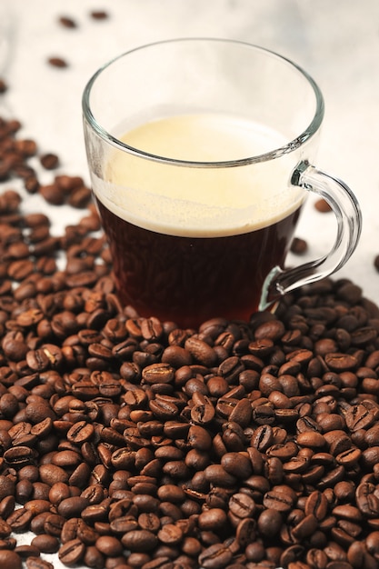 Café dans une tasse en verre sur le fond des grains de café