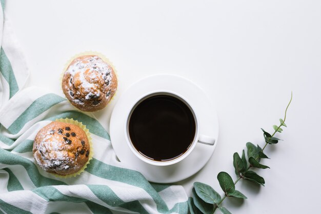 Café et deux muffins sur fond blanc