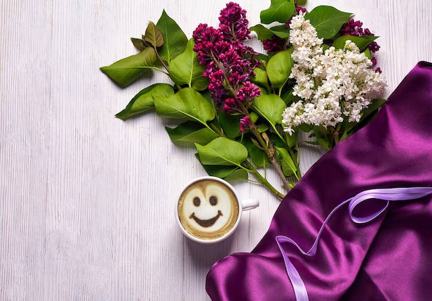 Café et différentes fleurs lilas sur fond blanc