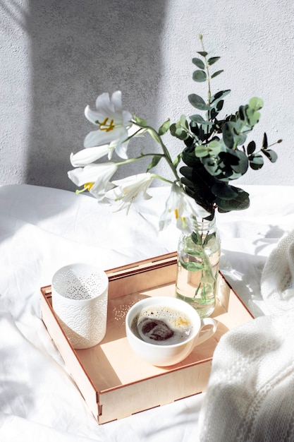 Café du matin au lit. Un plateau avec un bouquet de fleurs et de café sur un lit blanc.