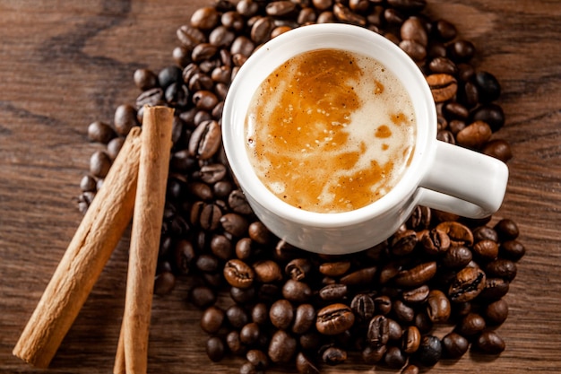 Café du matin Tasse à café cannelle et grains de café sur fond en bois Vue de dessus