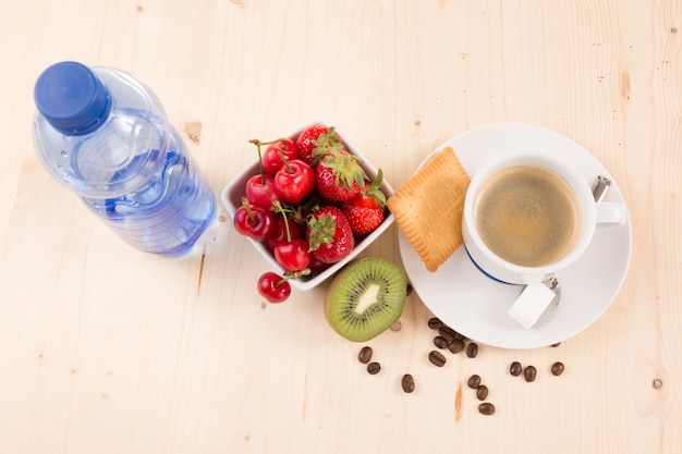 Café, eau, gâteau et fruits sur la table en bois