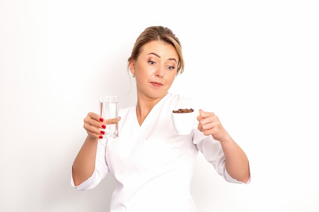 Café avec de l'eau la nutritionniste féminine tient une tasse de grains de café et un verre d'eau dans son ha