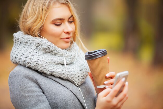 Café à emporter. Jeune femme avec un café dans le parc en automne