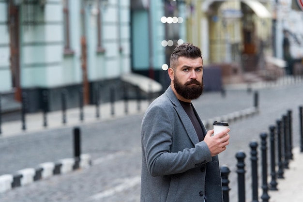 Le café est un câlin dans une tasse Homme d'affaires dans un style hipster tenant du café à emporter Boire sa tasse dès le matin Homme barbu appréciant le café du matin Hipster avec une tasse en papier marchant dans la ville