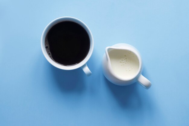 Café expresso et lait en pot sur fond bleu, vue de dessus, tendance des ombres.