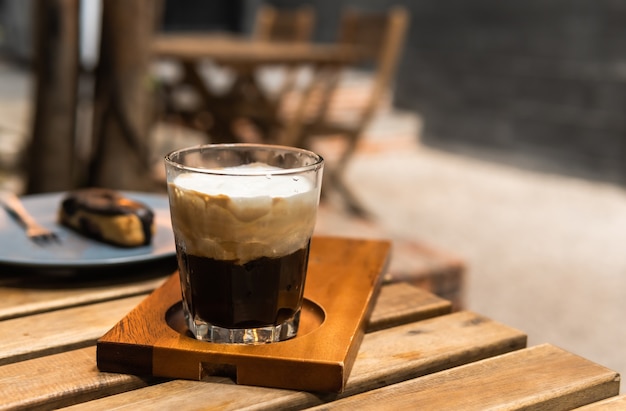 Café expresso traditionnel avec tasse de crème mousseuse blanche sur table en bois