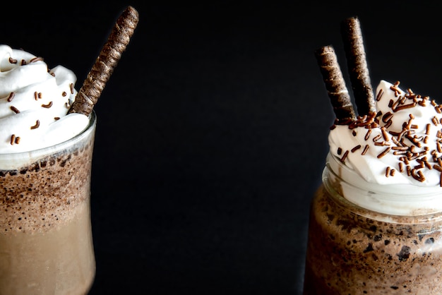 Café frappé froid avec crème fouettée. Fond noir avec frappuccino glacé.